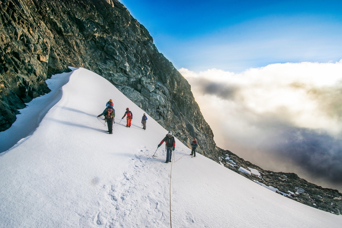 A photograph of tourists on the Rwenzori mountains captured during a hiking experience in Rwenzori Mountains National Park in Western Uganda.