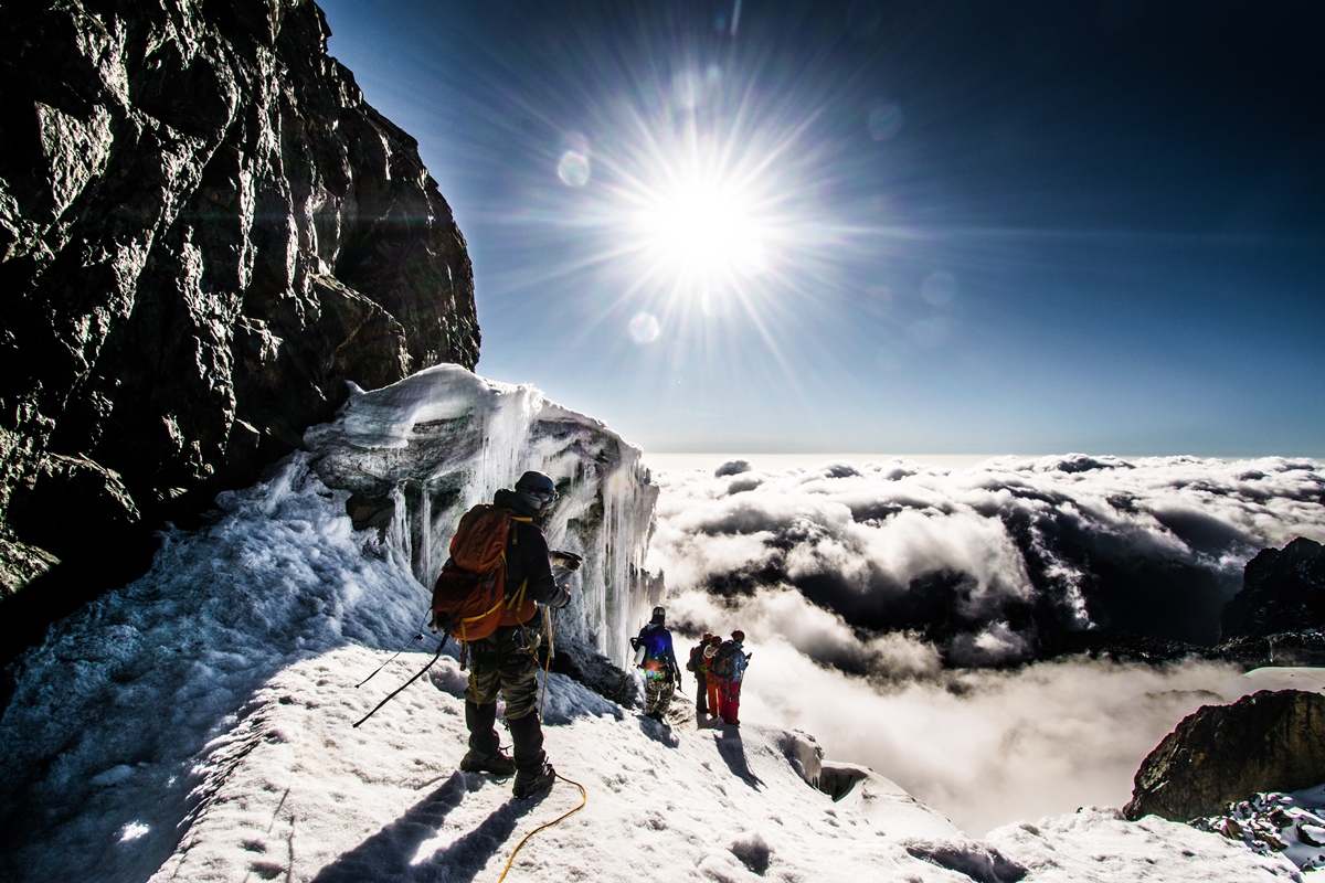 A photograph of tourists at the top of Rwenzori mountain ranges captured during a hiking experience in Rwenzori Mountains National Park in Western Uganda.