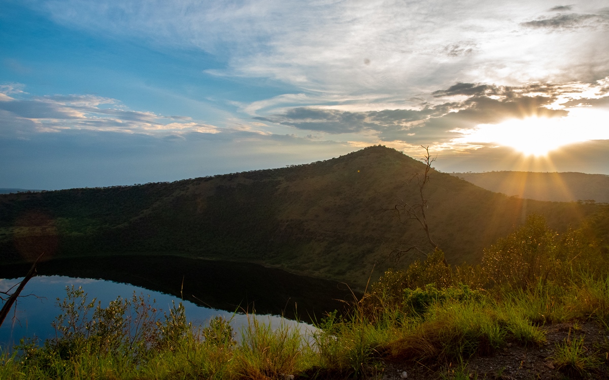 A photograph of the mountain ranges and a crater lake captured during the sunrise in Queen Elizabeth National Park in the Western Region of Uganda.