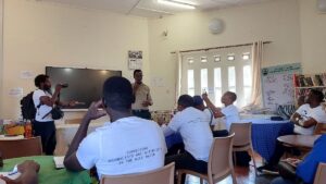 A photograph of an educator and his students in the Uganda Wildlife Conservation Education library Centre taken during an educational tour in Entebbe, Central Uganda