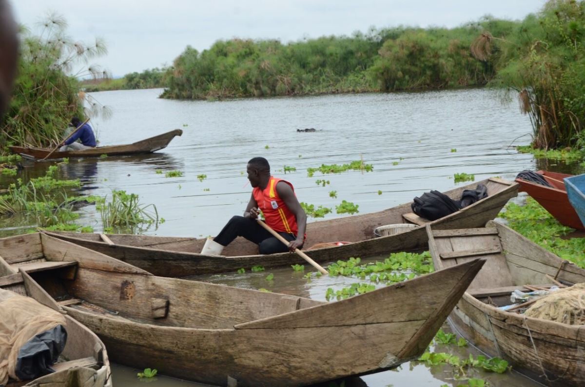 A photograph of fishermen in local boat canoes with a lake view in the background taken during a boat tour on Lake Wamala in Mityana in Central Uganda