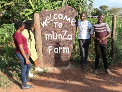 A photograph of visitors at the entrance to MLinza Farm in Zirobwe, Uganda.