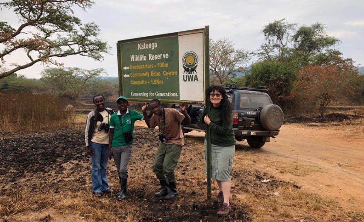 A photograph of tourists posing at the Katonga Wildlife Reserve signpost, Western Uganda