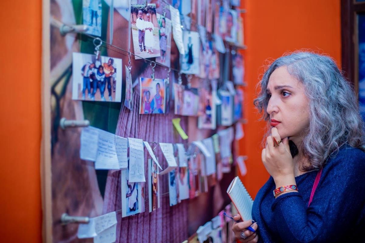 Photograph of a tourist viewing photos of the victims of the Kigali Genocide at the Kigali Genocide Memorial taken during a historical tour in Rwanda