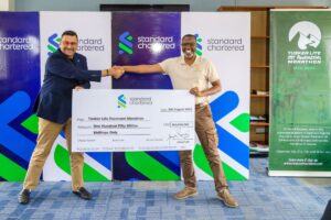 Photograph of the CEO of Standard Chartered Bank Uganda, Mr. Sanjay Rughani handing over a UGX 150 million cheque to Amos Wekesa, the Team Leader of the Rwenzori marathon
