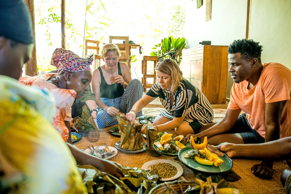 Photograph showing tourists getting served with traditional food during a cultural experience tour at Sentema Farm Lodge in Sentema Village in Wakiso District, Uganda