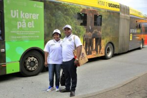 Ugandan tourism officials stand in front of an electric bus wrapped for the “Explore Uganda” campaign in Copenhagen