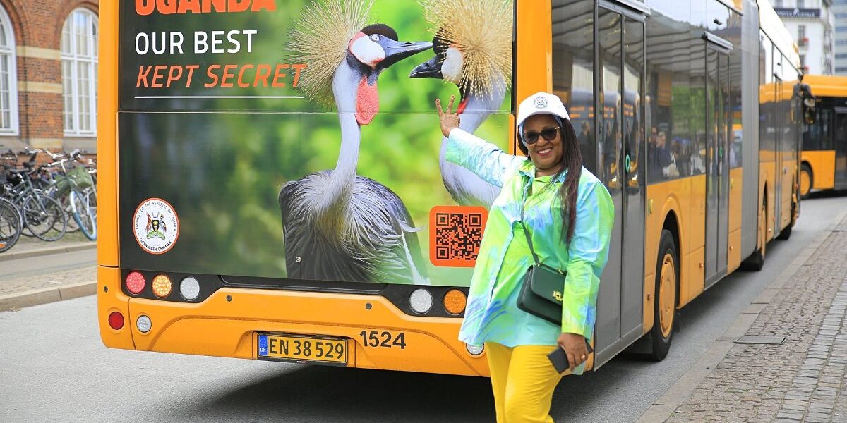 Uganda tourism representative proudly poses beside a campaign bus in Copenhagen