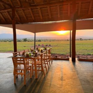 Dramatic sunset views from Namoni Lodge’s open-air dining area in Kidepo Valley National Park, Uganda. Guests can enjoy meals with sweeping savanna and mountain vistas