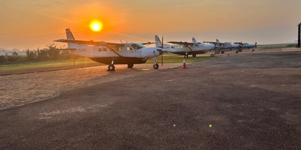 A row of Kampala Executive Aviation Cessna aircraft, including the Cessna 208 Caravan, lined up on the airfield at sunset, ready for scenic flights over Lake Victoria and the Entebbe peninsula
