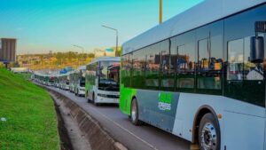 A convoy of white-and-green Kayoola EVS buses branded EBUS XPRESS travels in formation, highlighting Uganda’s locally manufactured 100% electric public transport fleet as it prepares for service on Ntinda-Kira and Namugongo corridors