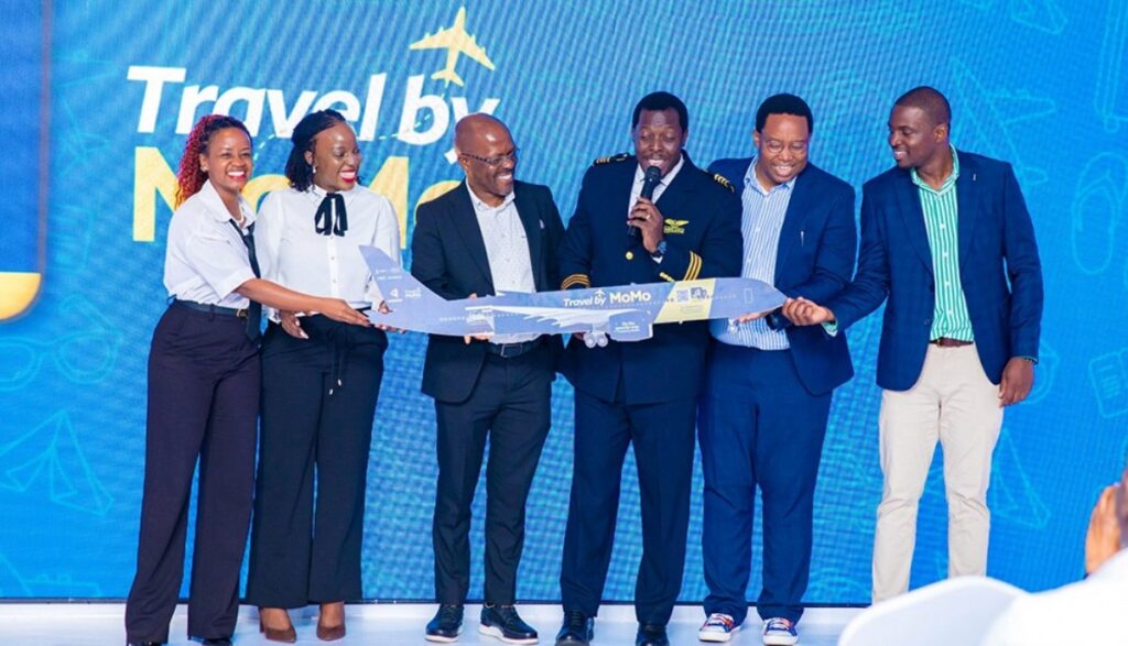 MTN MoMo and Next Travel officials, joined by a pilot, unveil a model aircraft branded “Travel by MoMo” during the official launch of the new digital flight booking platform in Uganda