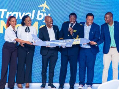 MTN MoMo and Next Travel officials, joined by a pilot, unveil a model aircraft branded “Travel by MoMo” during the official launch of the new digital flight booking platform in Uganda