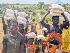 Community members in Karamoja carry vital food relief supplies following the 2026 Karamoja Hunger Run, turning solidarity into tangible support for families facing drought-related shortages
