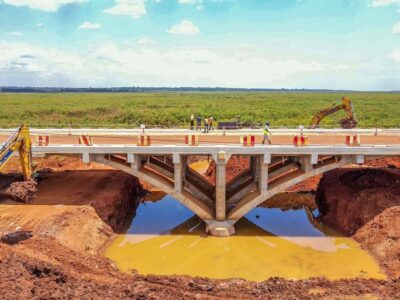 Close aerial perspective of the distinctive curved concrete arches of the new Ssezibwa Bridge, Uganda’s first of its kind, as excavators and construction teams advance remaining earthworks around the climate-resilient crossing New Ssezibwa Bridge