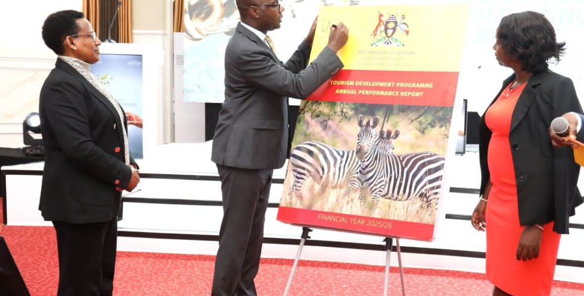 Finance Minister Hon. Henry Musasizi signs the Tourism Development Programme Annual Performance Report for Financial Year 2025/26 during the official unveiling at the 4th Annual Tourism Development Programme Review Conference, Imperial Royale Hotel, Kampala