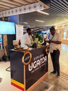 Uganda Tourism Board staff engage a visitor at the Explore Uganda booth during ExpoBéton RDC 2026 in Kinshasa, showcasing cultural products and Destination Uganda branding as part of efforts to strengthen regional tourism partnerships