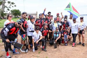 South African dragon boat team members pose with paddles and their national flag on the shores of Lake Victoria during the inaugural African Dragon Boat Racing competition in Kawuku, Wakiso District